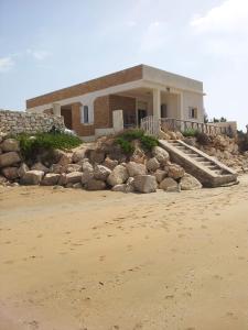a house on the beach with rocks in front of it at Sognare sul mare in Granelli