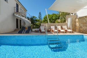 希杰弗朗吉卡Seaside apartments with a swimming pool Seget Vranjica, Trogir - 4284的房子旁边有带椅子和遮阳伞的游泳池