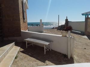 a bench sitting on a wall next to the beach at Sognare sul mare in Granelli