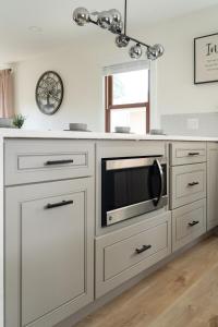 una cucina bianca con forno a microonde su un bancone di Modern Nest - Cozy & Free Parking a Edgewood Altre 26 foto