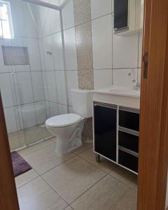 a white bathroom with a toilet and a sink at Recanto do Sossego in Barra Velha +7 photos