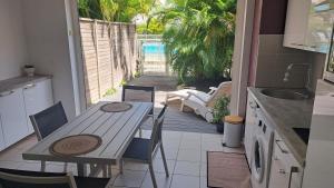 a kitchen with a table and chairs and a patio at Rêve Créole, accès piscine, plage et golf in Saint-François