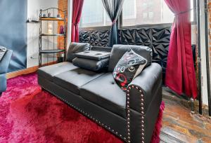 Un sofá de cuero negro en una habitación con una alfombra roja. en Beautiful 'Rose Themed' Loft Near Downtown Detroit apts, en Detroit