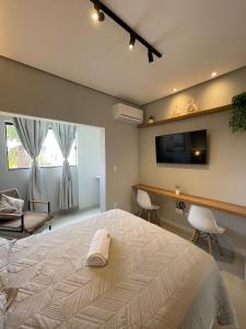 a bedroom with a bed and a desk and a television at Flat Executivo, Moderno e Aconchegante - Ahava Stays in Montes Claros