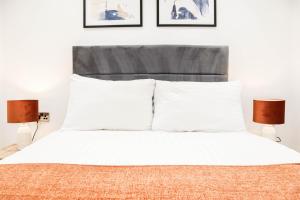 a bedroom with a bed with white sheets and two lamps at The Rye Retreat - 1BR Modern Design with Smart TV & Secure Underground Parking in Central High Wycombe HP13, Sleeps 3 in High Wycombe