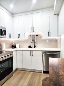 a white kitchen with white cabinets and a wooden floor at A true Home away from Home in Calgary