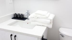 a white bathroom with a sink and white towels at A true Home away from Home in Calgary