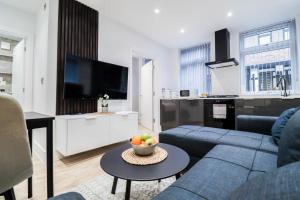 a living room with a blue couch and a tv at The Rye Retreat - 1BR Modern Design with Smart TV & Secure Underground Parking in Central High Wycombe HP13, Sleeps 3 in High Wycombe