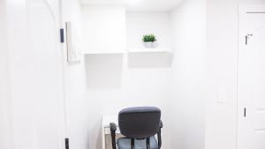 a black chair in a white room with a potted plant at A true Home away from Home in Calgary