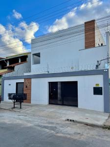 a white building with a parking lot in front of it at Flat Executivo, Moderno e Aconchegante - Ahava Stays in Montes Claros