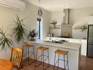 a kitchen with a white counter top and stools at Warm, sun filled apartment in Albert Town +5 photos