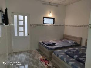 隆海Thiên Thanh Long Hải Motel的配有窗户和门的客房内的两张床 更多15张照片