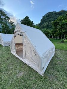 une tente blanche sur l'herbe dans un champ dans l'établissement Moorea camping Valley, à Moorea