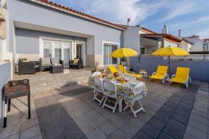 a patio with a table and chairs and yellow umbrellas at LS Beach House in A dos Cunhados