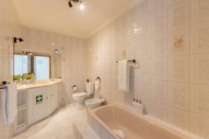 a bathroom with a tub and a toilet and a sink at LS Beach House in A dos Cunhados