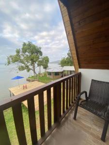 a balcony with a bench and a view of the water at Chalé na beira da lagoa com vista in Imbituba