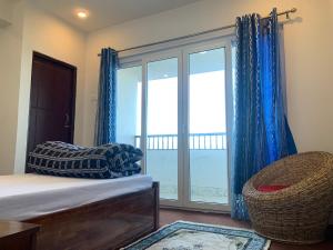 a bedroom with a bed and a large window at Begonia Homestay Darjeeling in Darjeeling