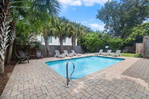 a swimming pool with chaises and chairs in a yard at CA411: 411 Carolina Blvd. in Isle of Palms