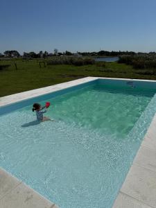 une jeune fille joue dans une grande piscine dans l'établissement Casa con Piscina sobre Laguna Brava - Tranquilidad y Naturaleza en Barrio Privado, à Corrientes