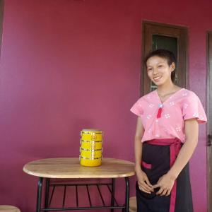 Una donna è in piedi accanto a un tavolo di Bua Patumma Resort a Mae Sai