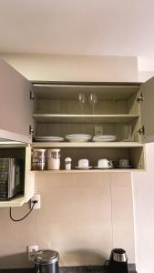 a kitchen with white cabinets with plates and dishes at Graphite One - Frente metro Luz com Estacionamento in Sao Paulo