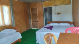 um quarto com duas camas, uma mesa e cadeiras em Dibru-Saikhowa Homestay em Tinsukia