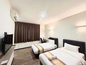 a hotel room with two beds and a flat screen tv at Collection O Malacca Near St John's Fort Formerly Gill Garden in Melaka