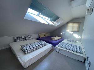 two beds in a small room with a skylight at 뚠하우스3 in Samgong
