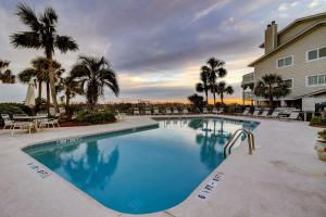 a large swimming pool with chairs and palm trees at SG7A: 7A Seagrove Villa in Isle of Palms