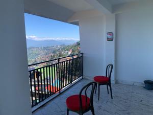 a balcony with two chairs and a view of a city at Begonia Homestay Darjeeling in Darjeeling