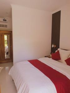 a bedroom with a large bed with red and white sheets at GYANA House in Ubud