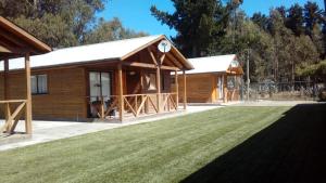 a log cabin with a lawn in front of it at Cabañas Sol de Buchupureo in El Cerrillo +10 photos