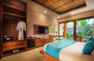 a bedroom with a bed and a tv and a bed and a television at Sagara Candidasa by AHM in Candidasa