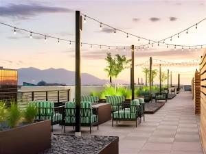 214 North Temple CondominiumModern Downtown 2BR 2BA with City Views Fire Pit Walk to Delta Center的一张露台效果图，配有绿色椅子和灯光。