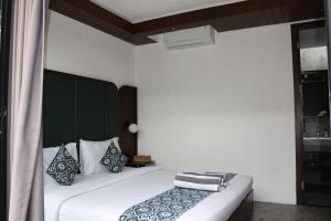 a bedroom with a white bed with a green headboard at Lovely 3 Bedroom Villa in Ubud - Artha Loka OA in Ubud