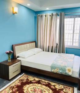 a bedroom with a bed with blue walls and a window at Sanjog's B&B in Bhaktapur