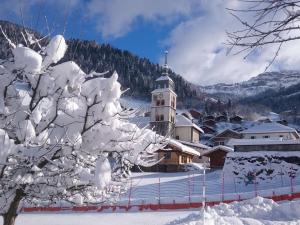 a building in the snow with a snow covered tree at Charmant T2 au centre avec parking et WIFI - FR-1-342-340 in Arêches