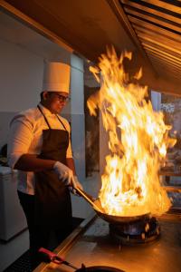 a chef cooking food in a pan with fire at Breedon Residence Hotel in Anuradhapura