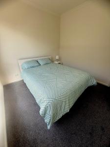 a bedroom with a bed with a green and white comforter at Peaceful Private Room in Wyndham Vale in Wyndham Vale