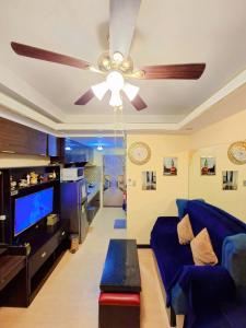 a living room with a blue couch and a ceiling fan at Trees Residences by Cail in Manila