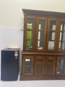 a large wooden cabinet with glass doors next to a refrigerator at Cantique Homestay in Mantin +2 photos