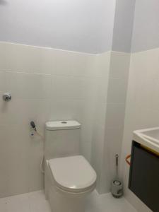 a white bathroom with a toilet and a sink at Cantique Homestay in Mantin