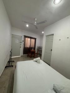 a bedroom with a white bed with a ceiling fan at DePARTAMENTO AF16 in Tizimín