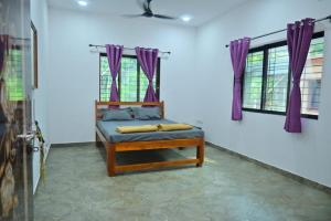 ein Zimmer mit einem Bett und lila Vorhängen in der Unterkunft Kokan beach cottage in Alibag + 4 Fotos