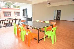 ein Esszimmer mit einem Tisch und bunten Stühlen in der Unterkunft Kokan beach cottage in Alibag