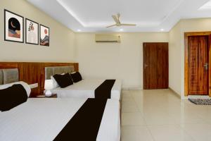 a hotel room with two beds and a ceiling fan at Super Townhouse Varanasi City Station Formerly S Kumar Inn in Varanasi