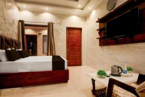 チャンディーガルにあるSuper Townhouse Naya Gaon Formerly Hotel Paradiseのベッドと薄型テレビのある寝室
