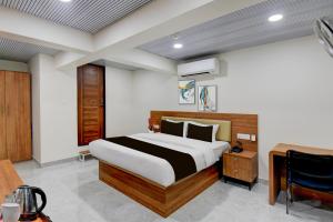 um quarto com uma cama e uma escrivaninha em um cômodo em Super Hotel O Pune Kasarwadi Railway Station em Pune