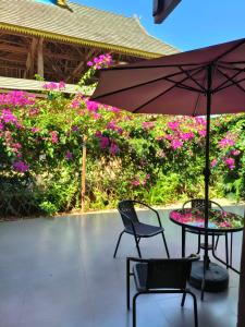 a patio with a table and chairs and pink flowers at Jinghong Manyun Dai Village Inn in Jinghong