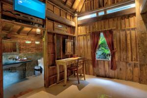 Cette chambre dispose d'une table et d'une télévision murale. dans l'établissement Sweet Orange Pondok, à Ubud